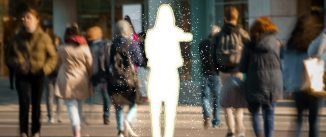 People walking on a city street. One of them is missing, with only a white cut-out of her shape left behind.