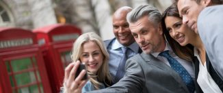 Group of business people taking a selfie outdoors with a smart phone