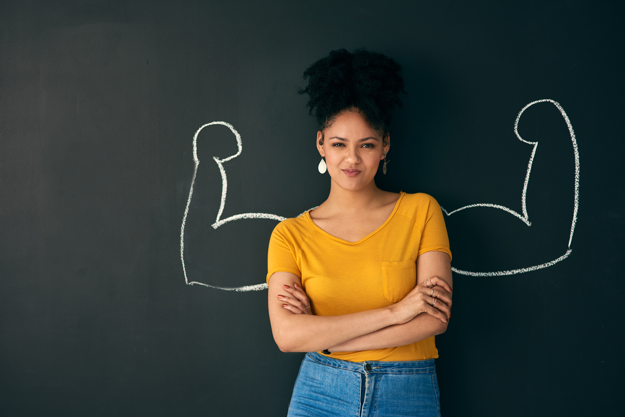 Shot of a woman posing with a chalk illustration of flexing muscles against a dark background