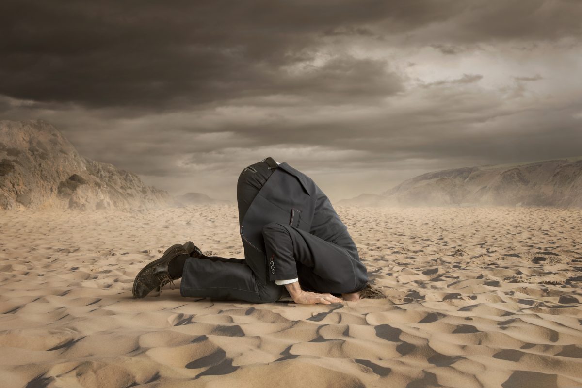 A businessman with his head in the sand like an ostrich