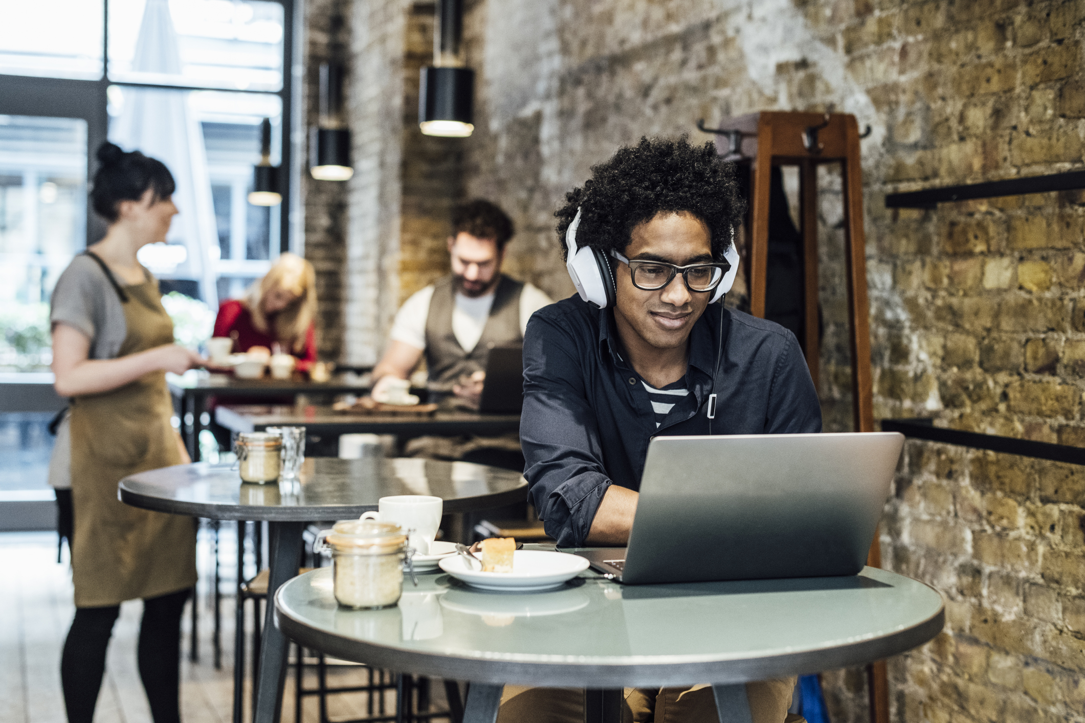 Young man using laptop in cafe and listening to music