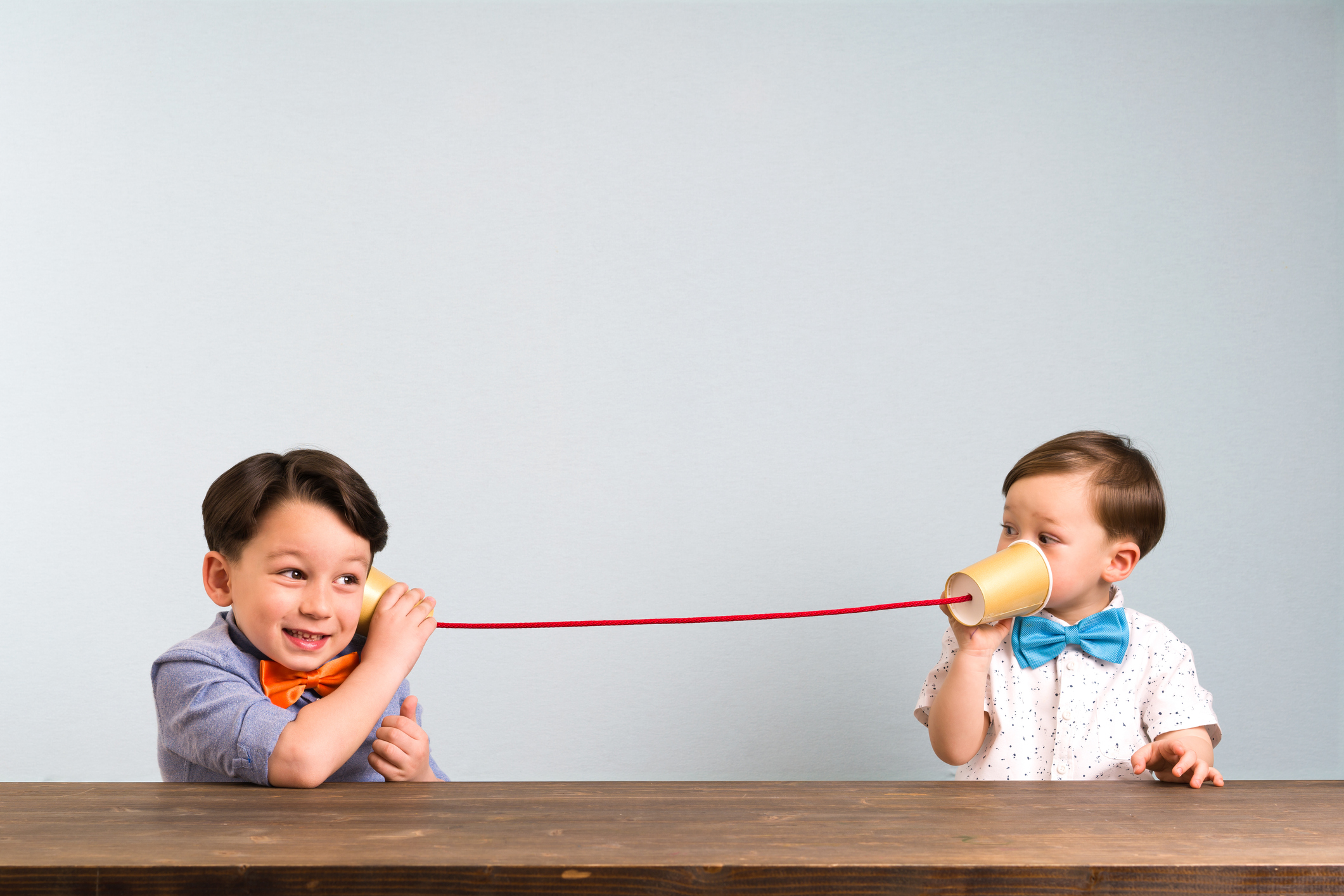 Two childeren are using paper cups as a telephone