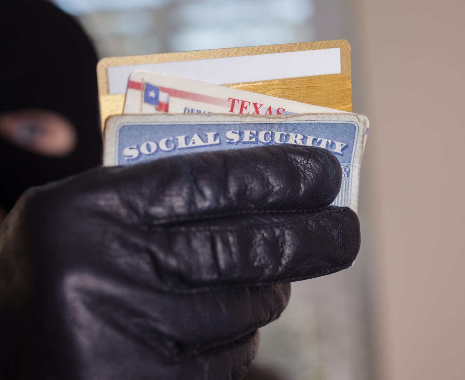 Masked theif steals a victim's identification cards.