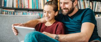 father and daughter having fun with digital tablet on couch