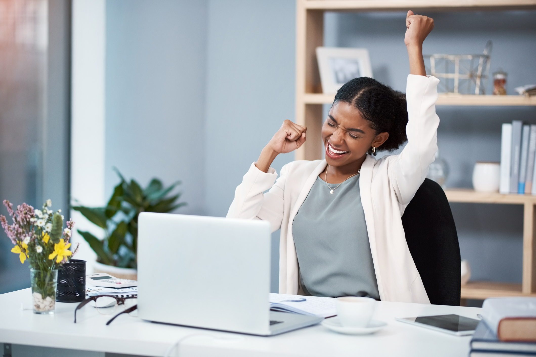 Shot of a happy young businesswoman celebrating at her desk in a modern office