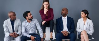 Studio shot of a group of corporate businesspeople waiting in line against a gray background