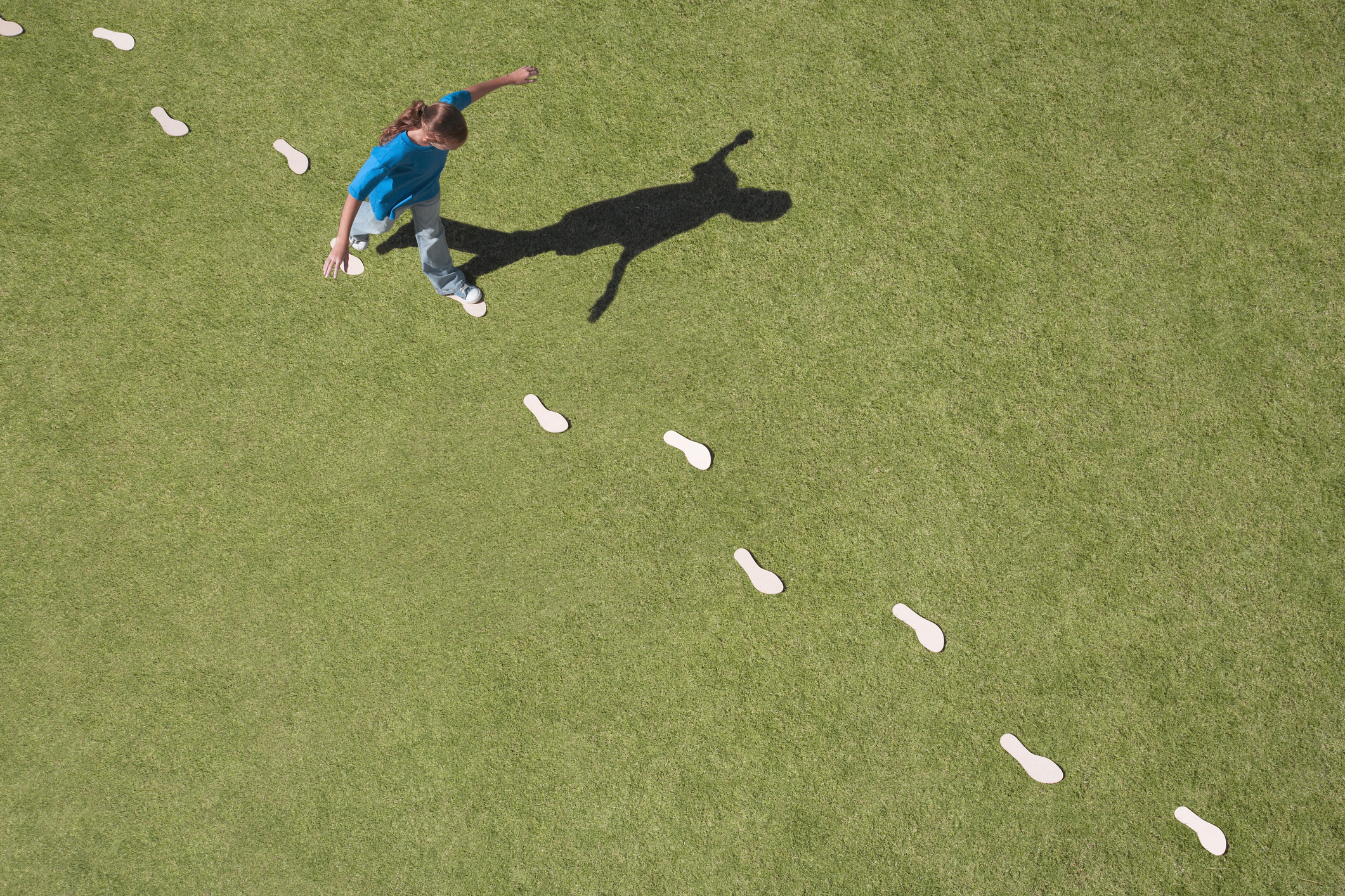 Young girl following footprints on grass