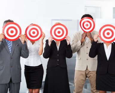 Group Of Businesspeople Holding Dartboard In Front Of Face