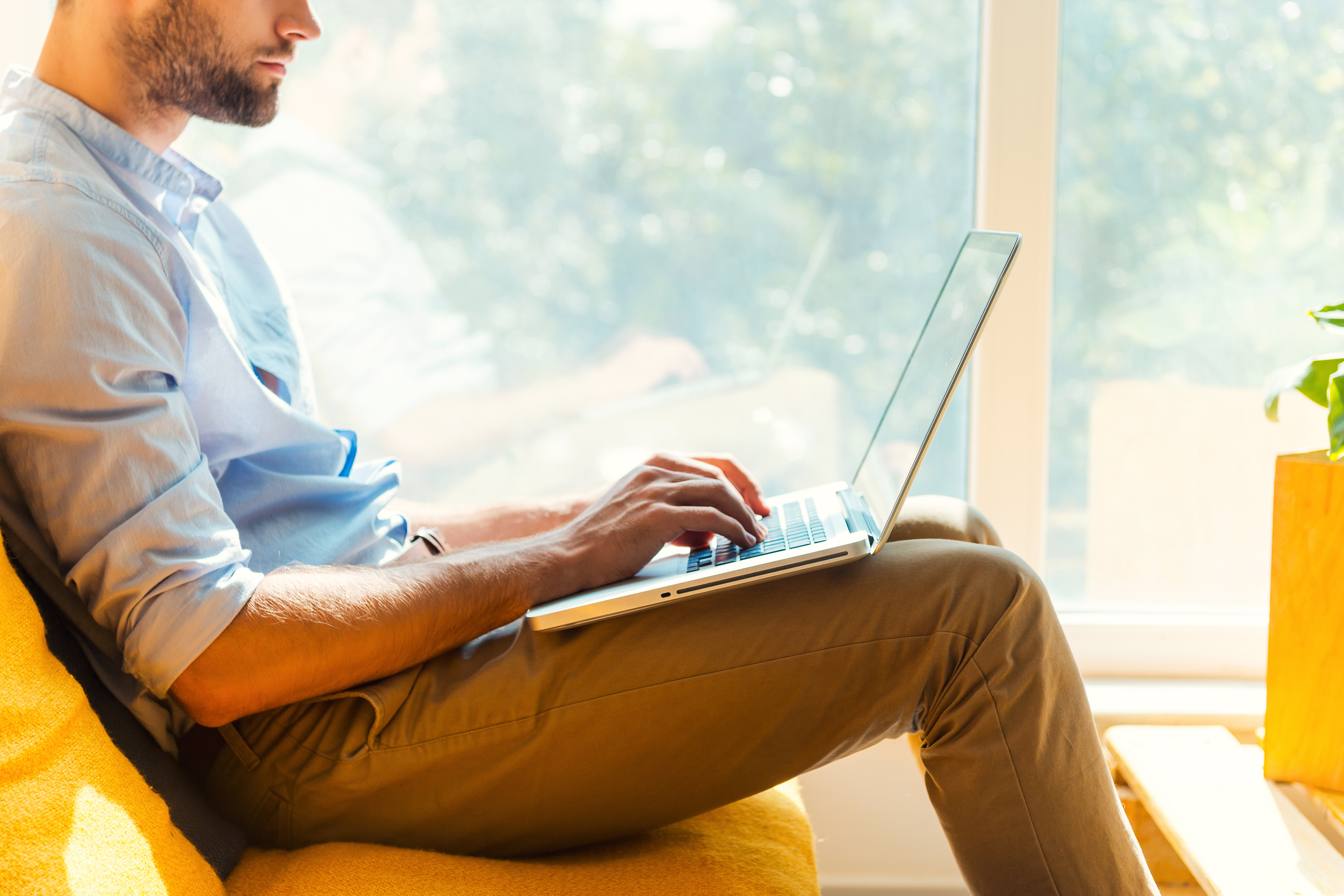 Close-up of young man working on laptop while sitting in the rest area of the office