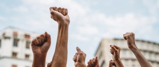 People with raised fists at a demonstration in the city. Multi-ethnic group of people together on strike.