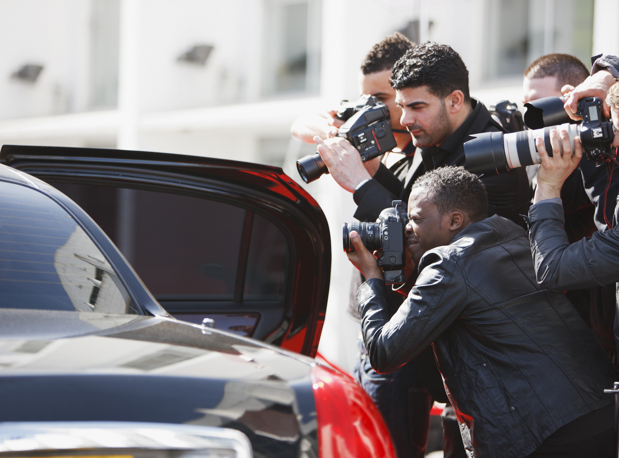 Paparazzi taking pictures of celebrity in car