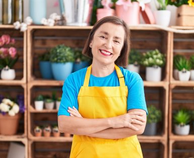 Proud woman standing in front of gardening business shelves.