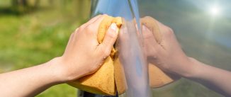 The employee of the car wash washes the car.