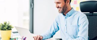 Happy man working on laptop at corporate office